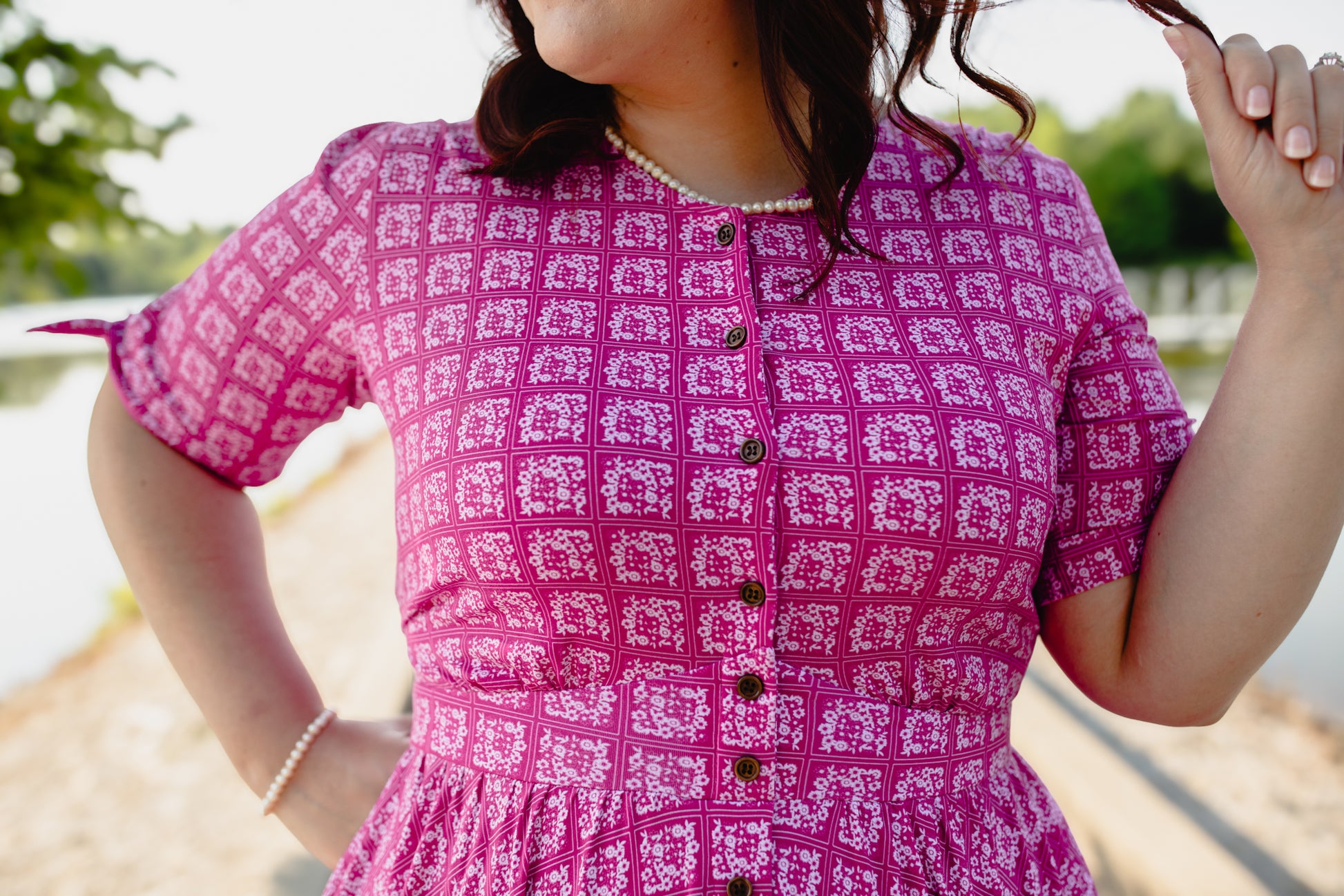 Person wearing a pink patterned modest nursing dress with a blurred outdoor background