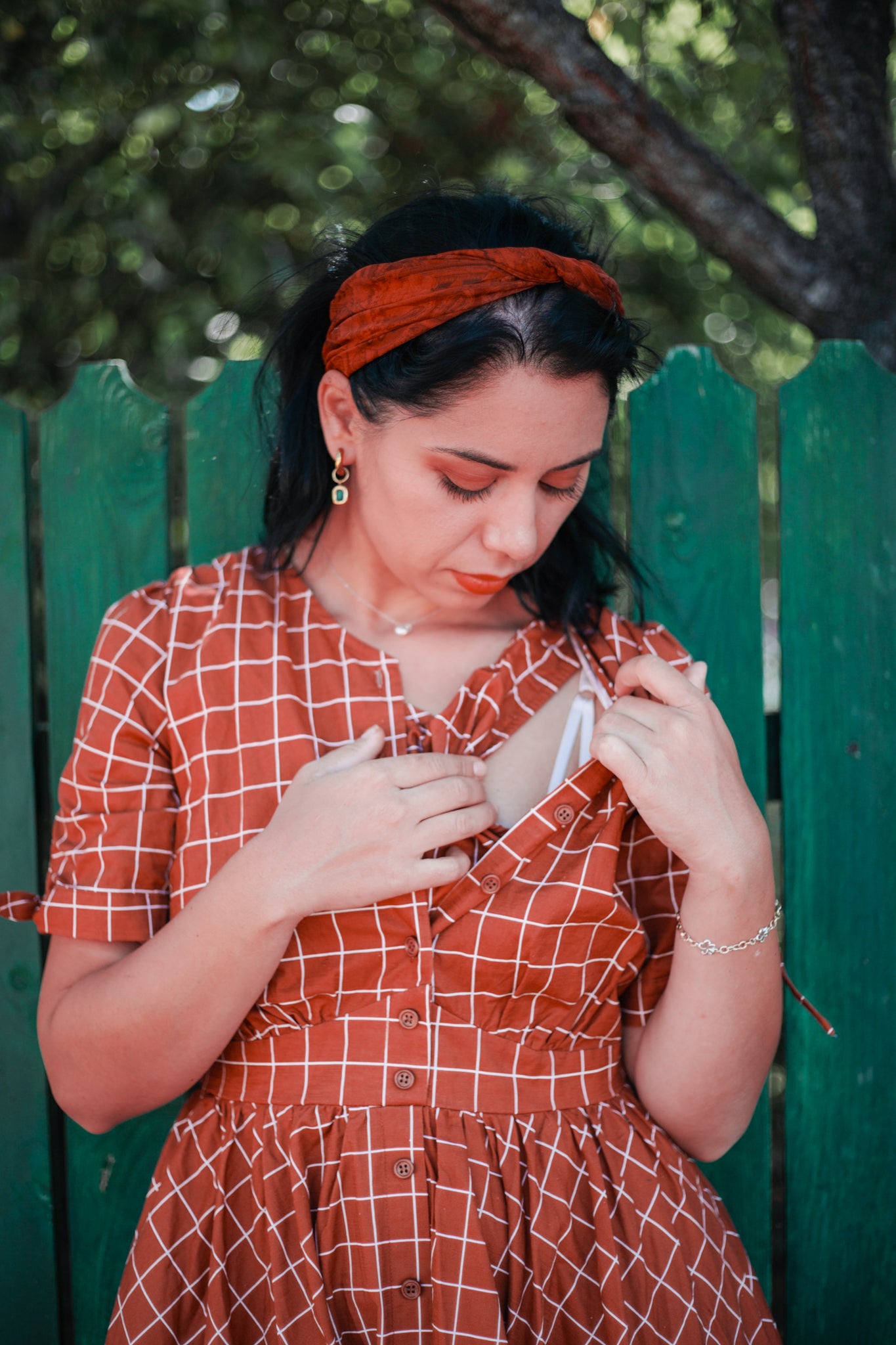 Woman in modest nursing red checkered dress fence