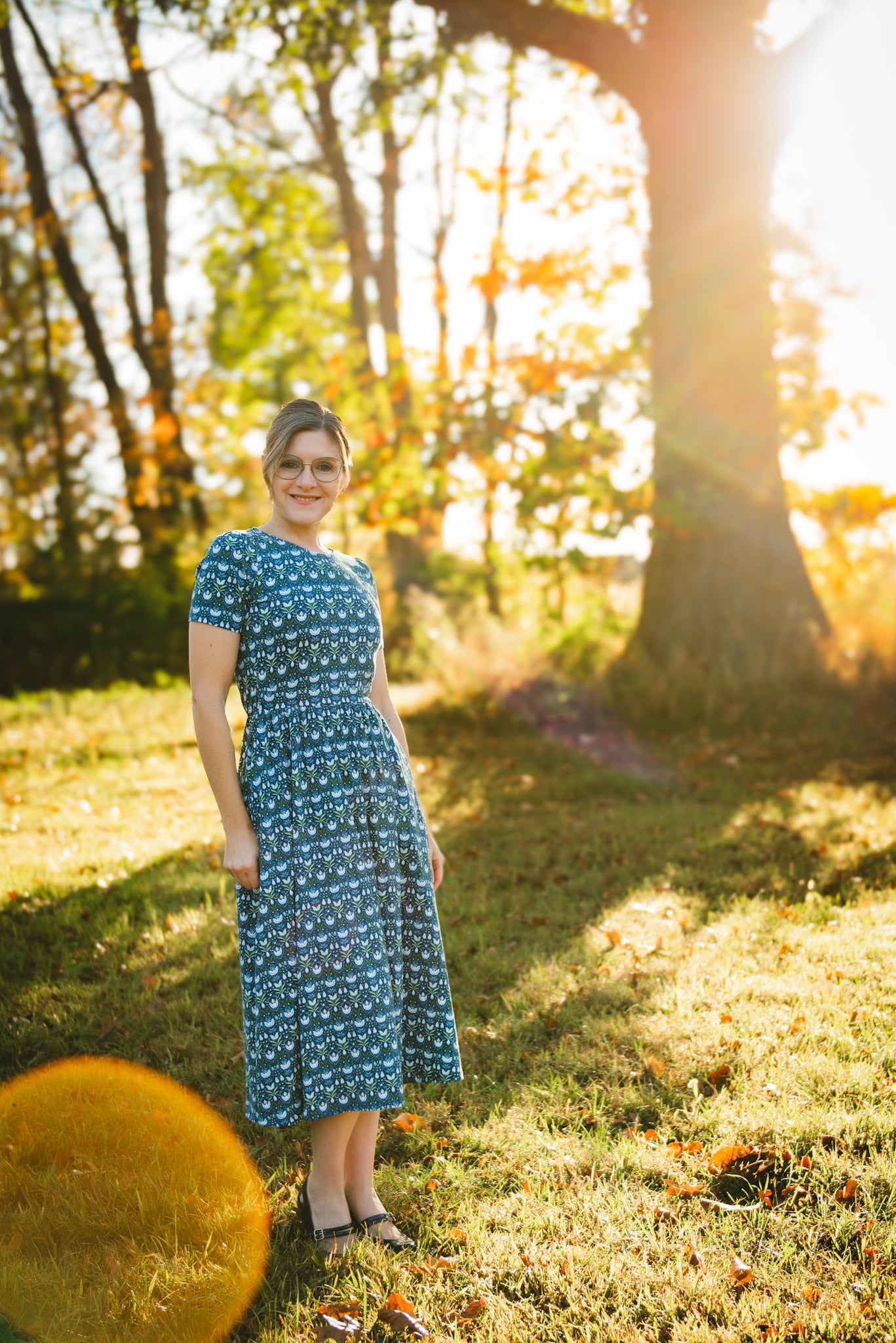 Woman in modest nursing dress, sunlit forest.