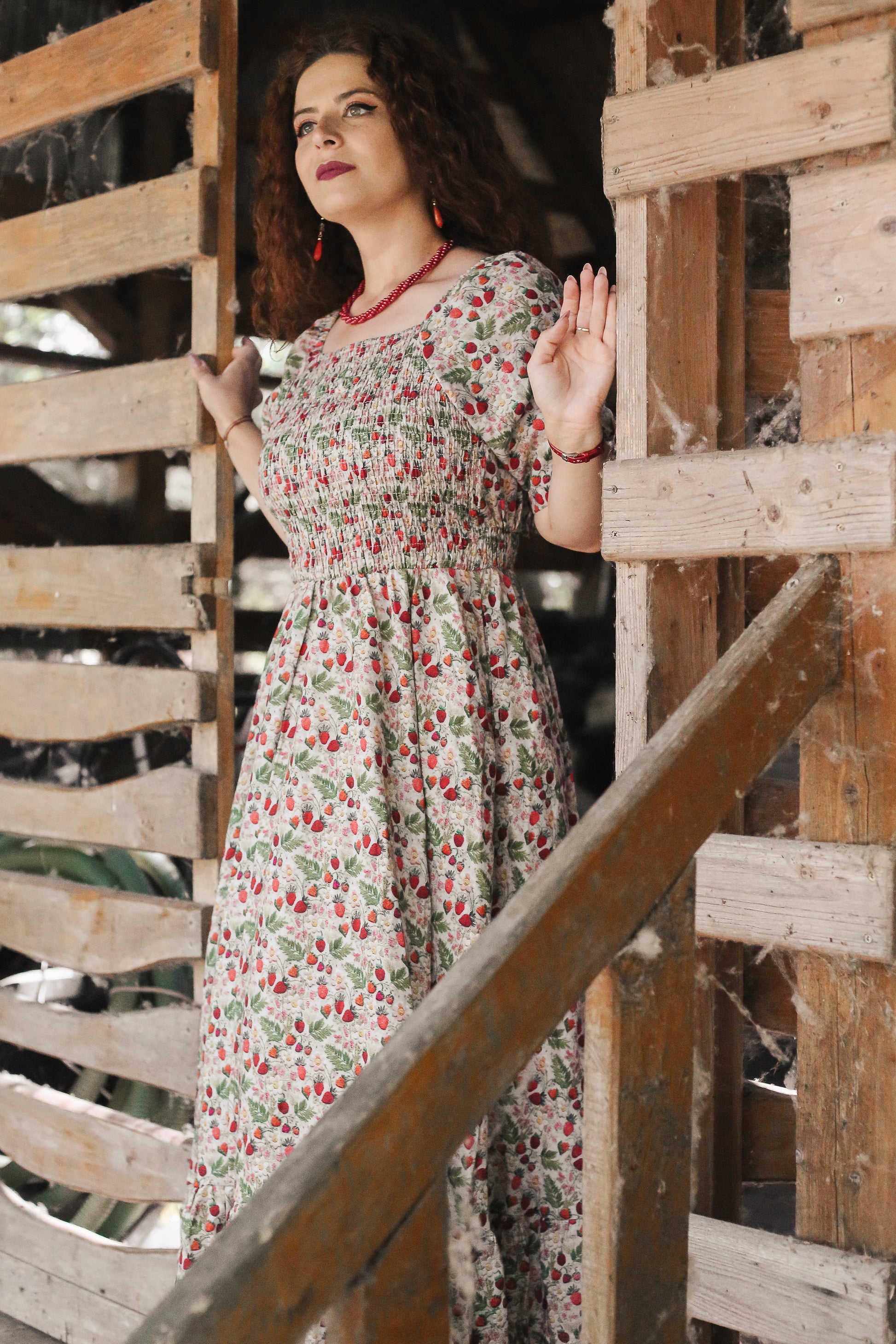 Woman in a floral modest nursing dress standing behind wooden lattice
