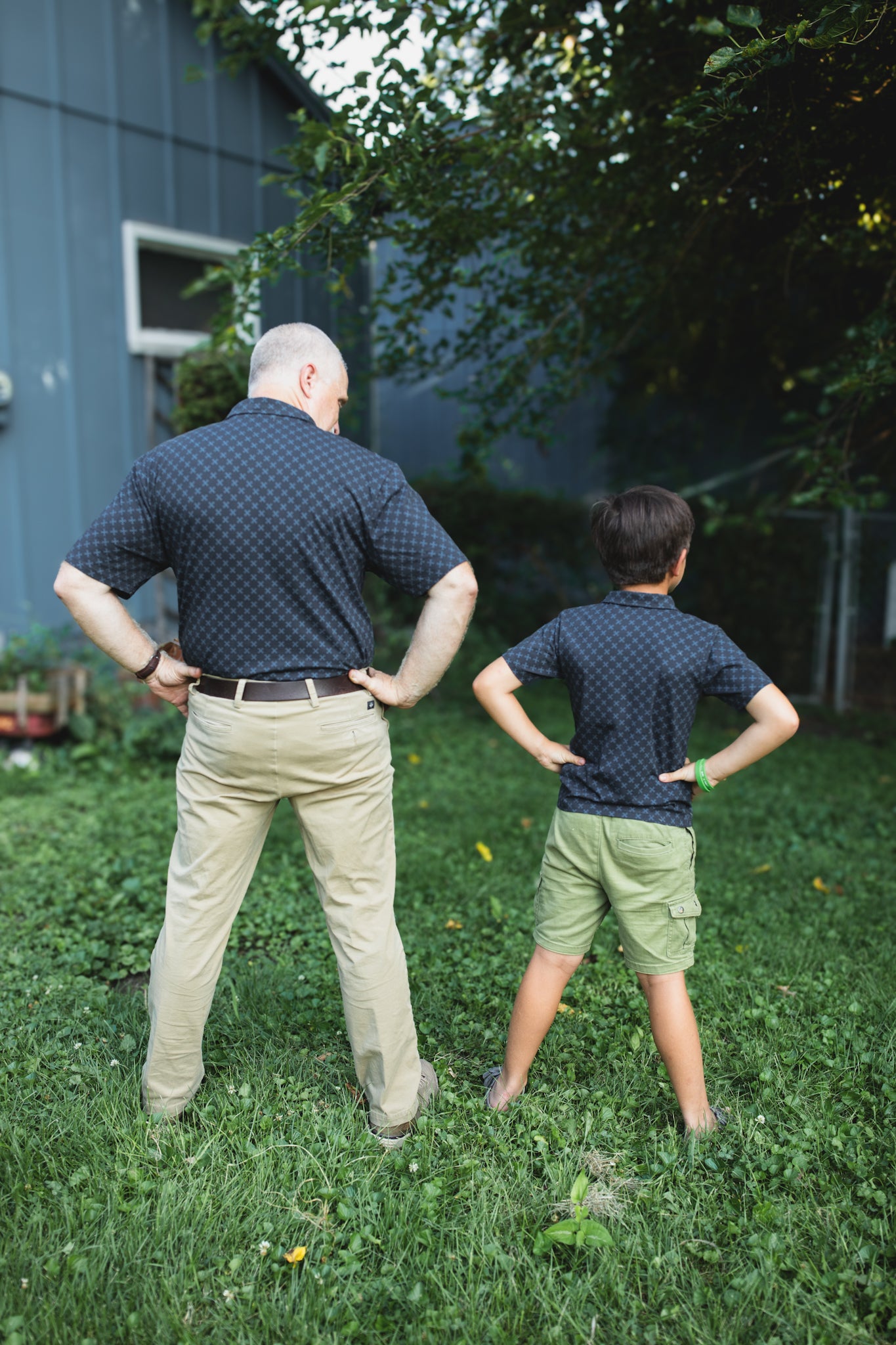 Young boy wearing a dark blue polo shirt with his father in a matching shirt
