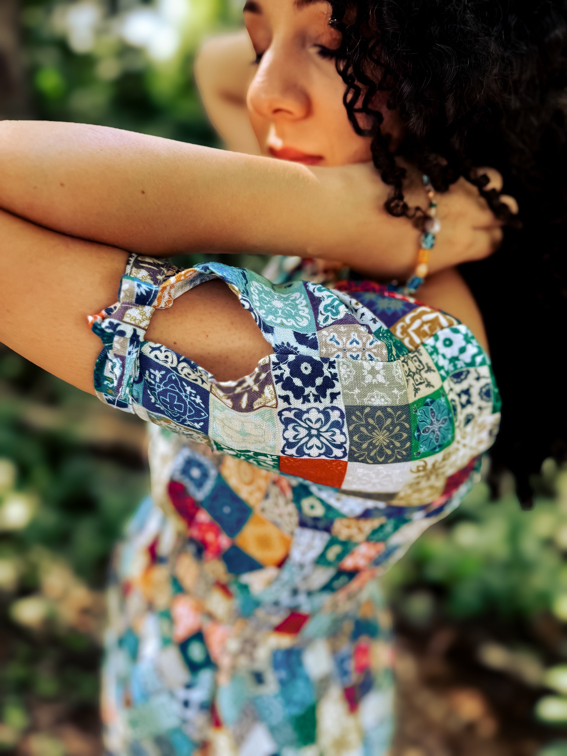 Woman wearing a colorful patchwork modest nursing dress with a blurred natural background