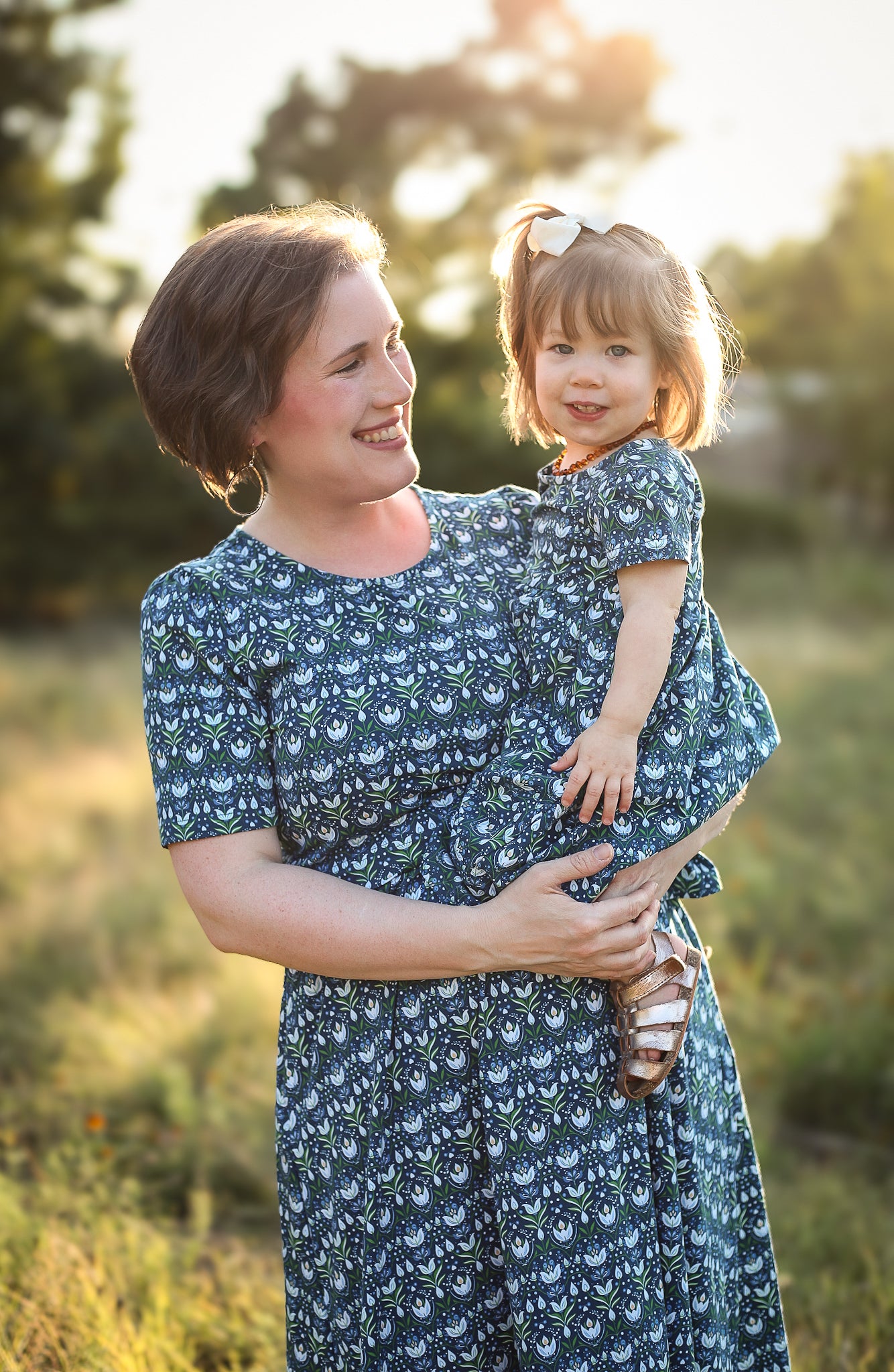 Woman holding a child in modest nursing dress outdoors