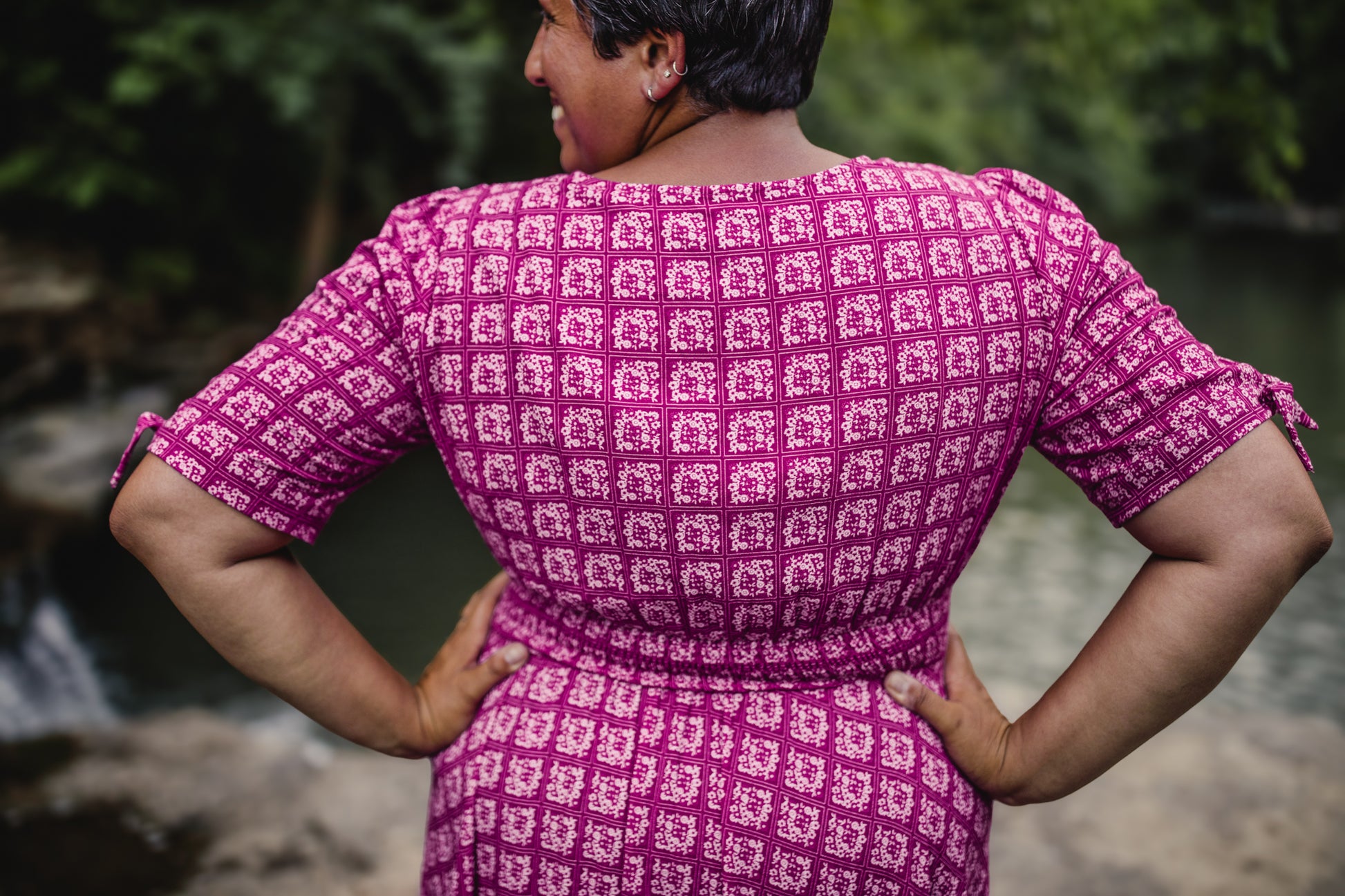 Person wearing a pink patterned modest nursing dress with a blurred natural background