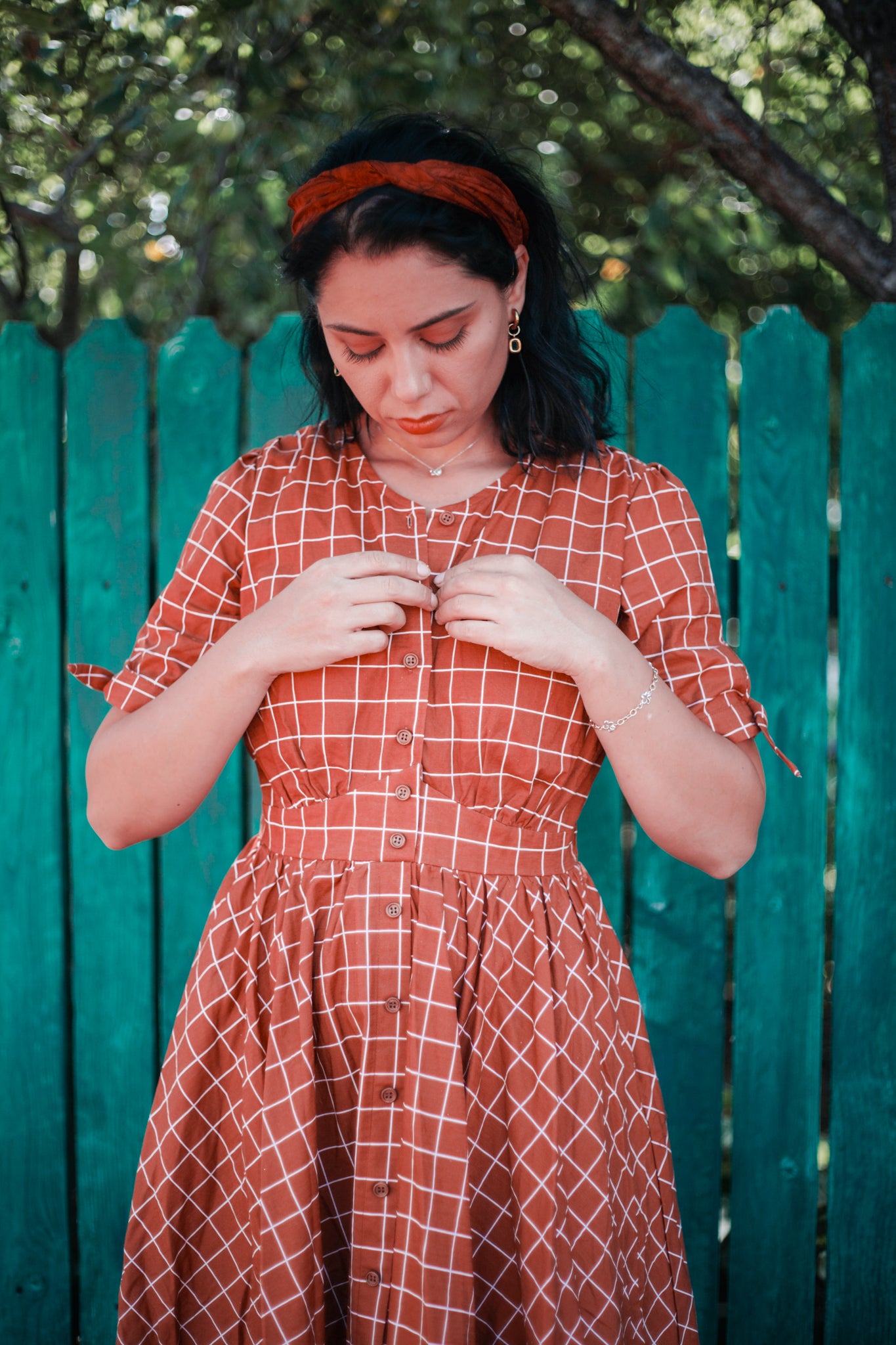 Woman in modest nursing checkered dress near fence