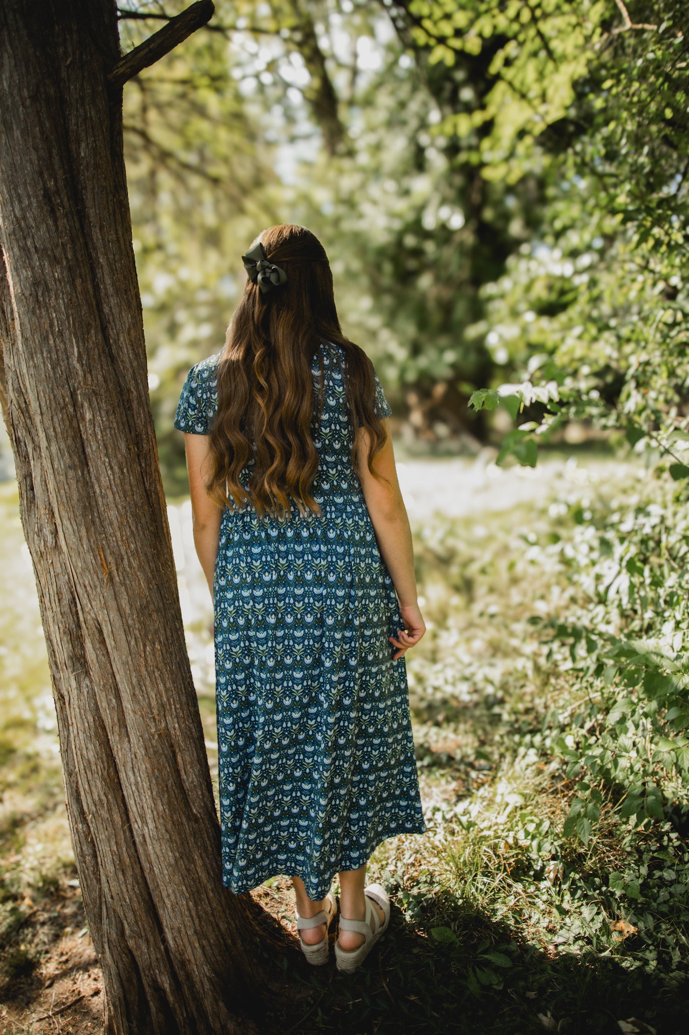 Woman in modest nursing blue floral dress under tree