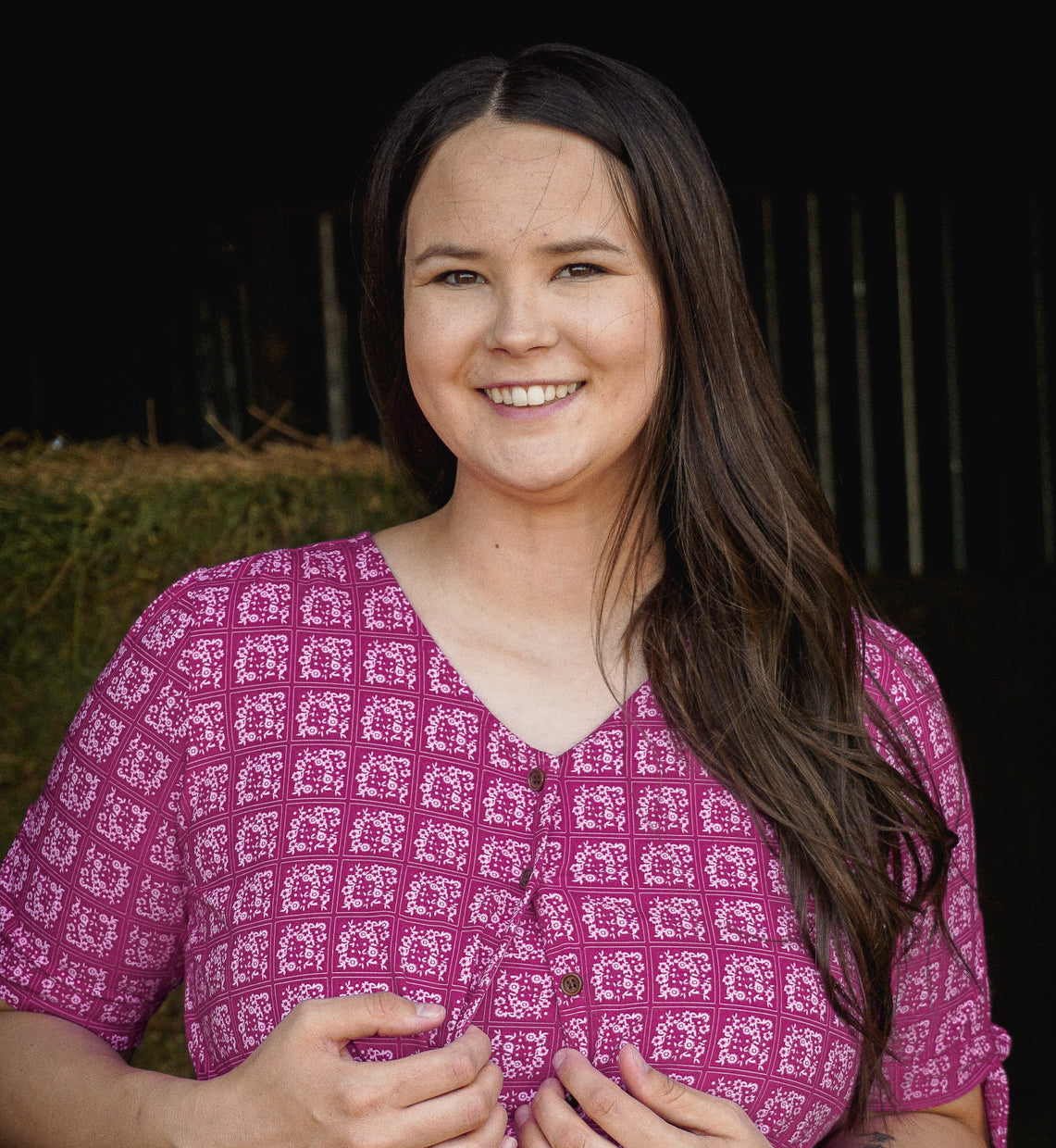 Woman wearing a pink patterned modest nursing dress with a dark background