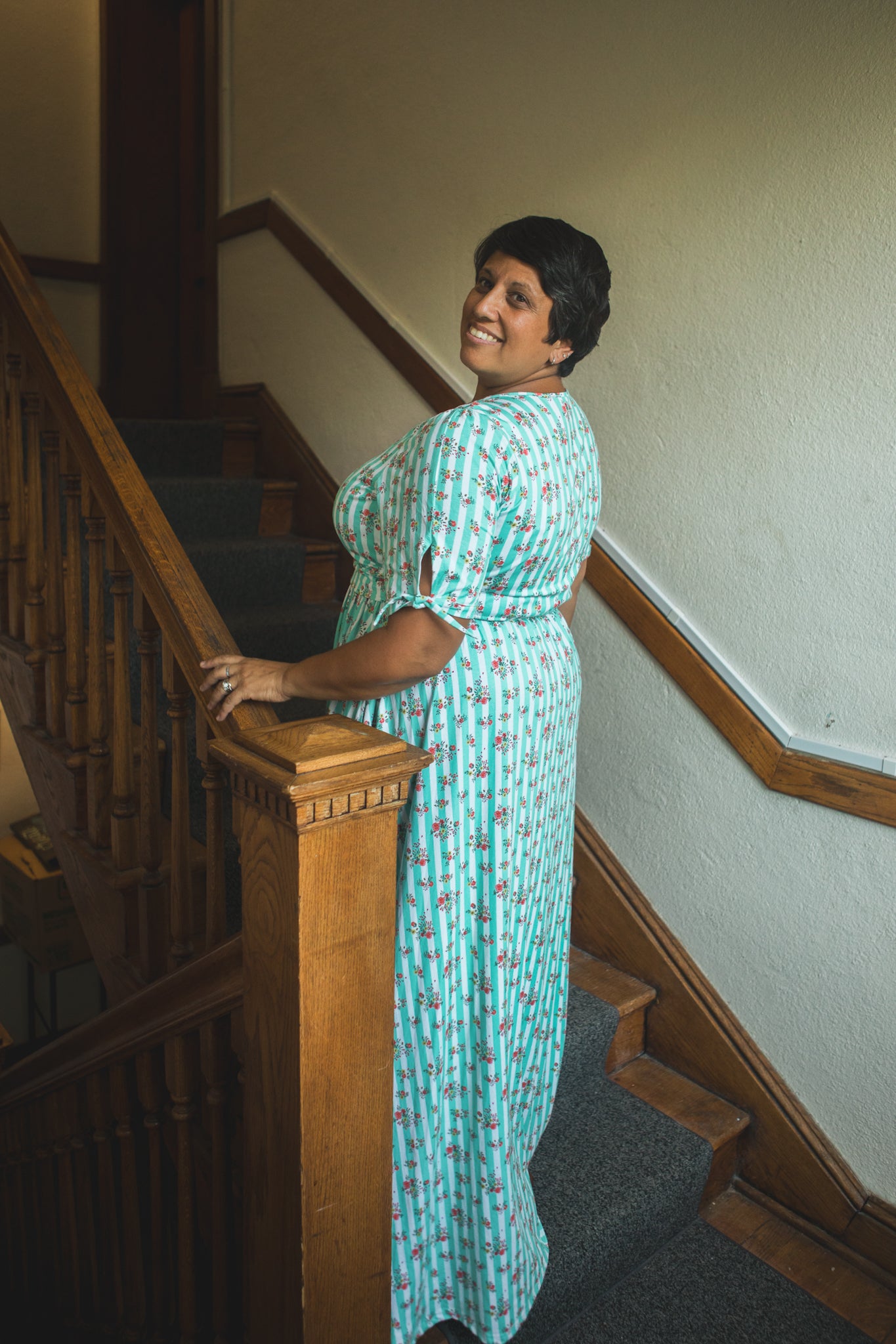 Woman in a green modest nursing dress standing on a staircase