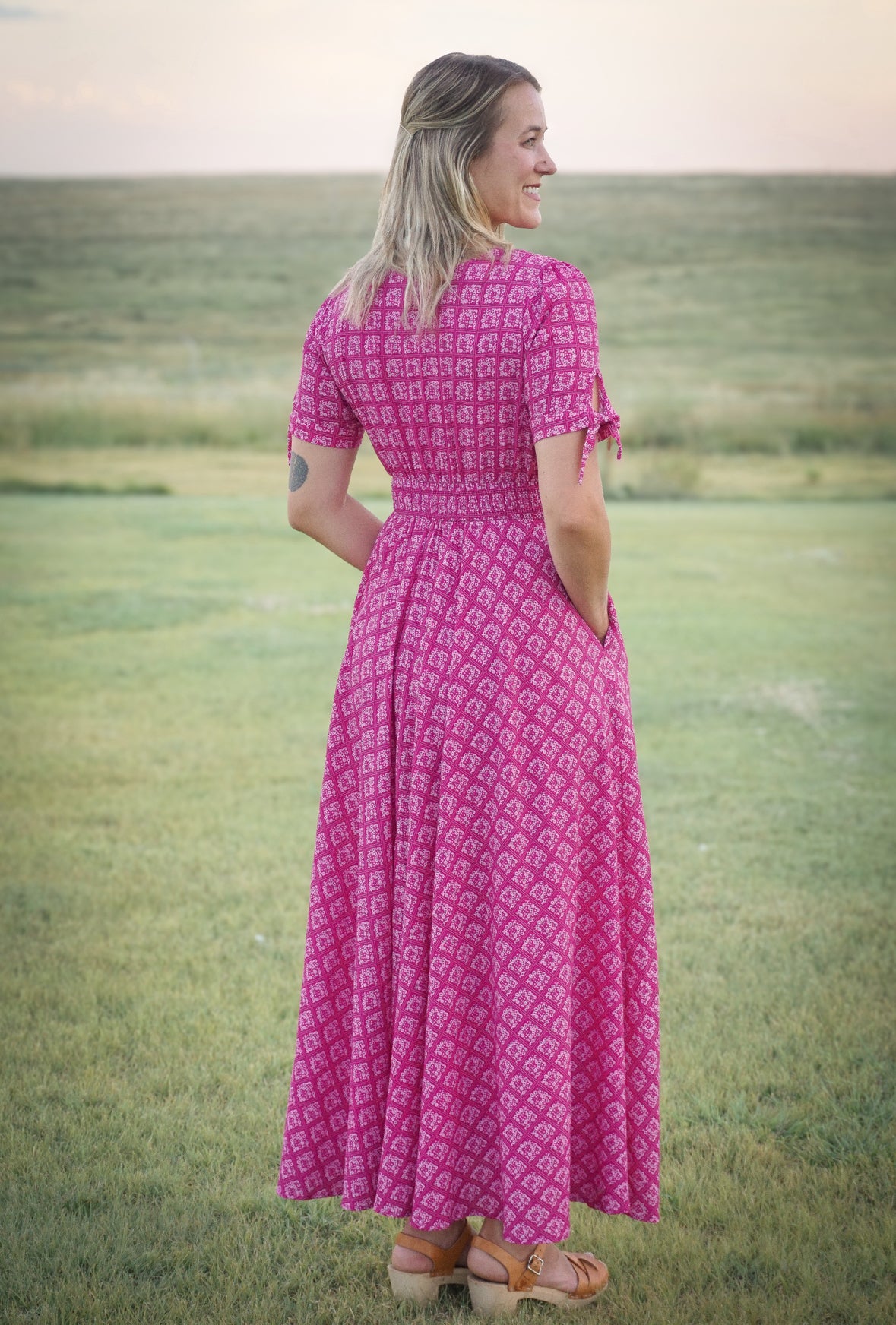 Woman in a pink modest nursing dress standing in a field