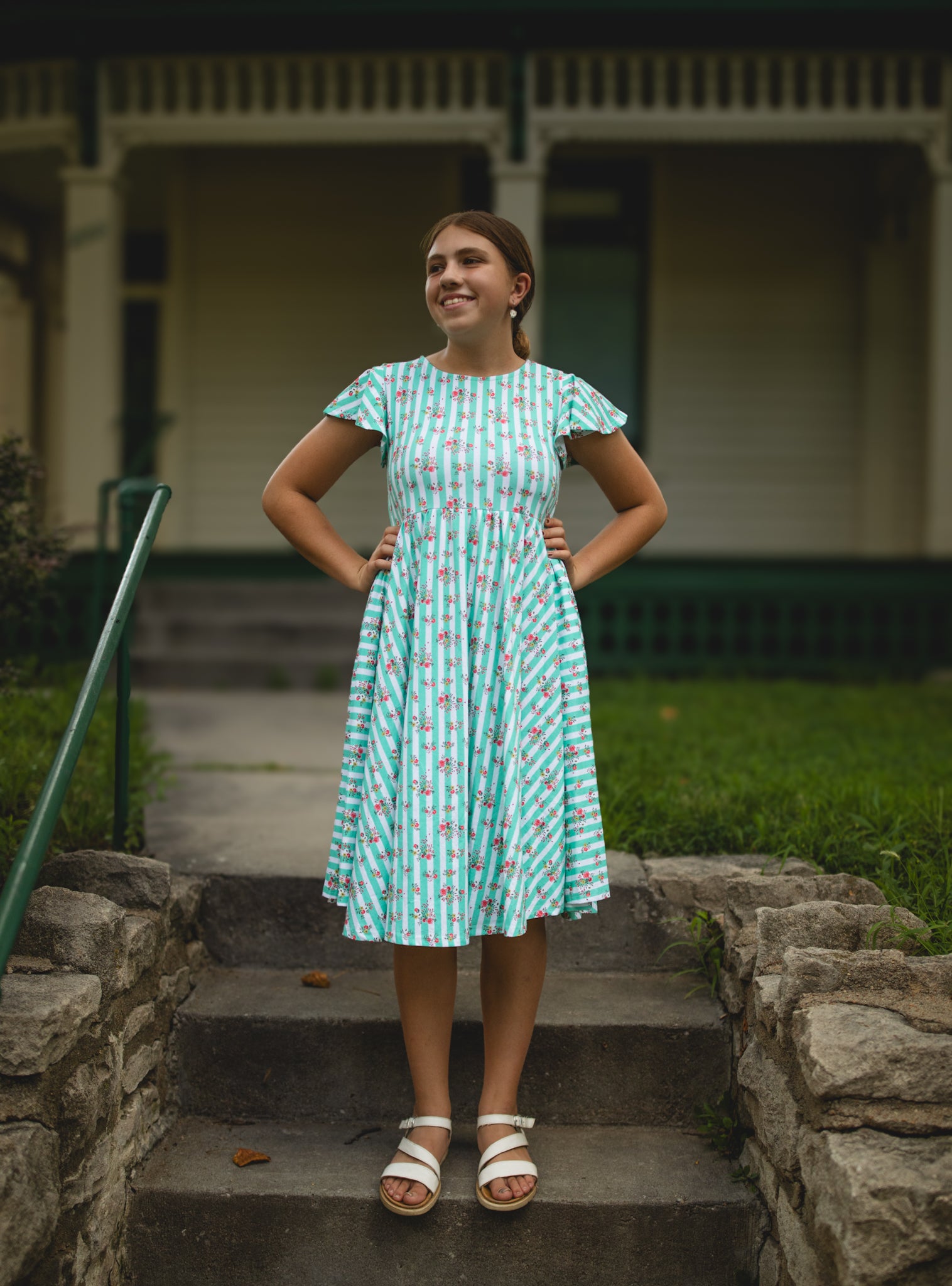Woman in a patterned modest dress standing on stone steps outdoors
