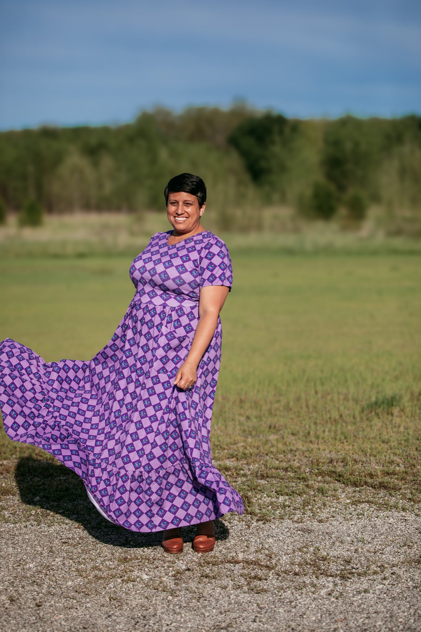Person wearing a purple patterned modest nursing dress standing in a field.