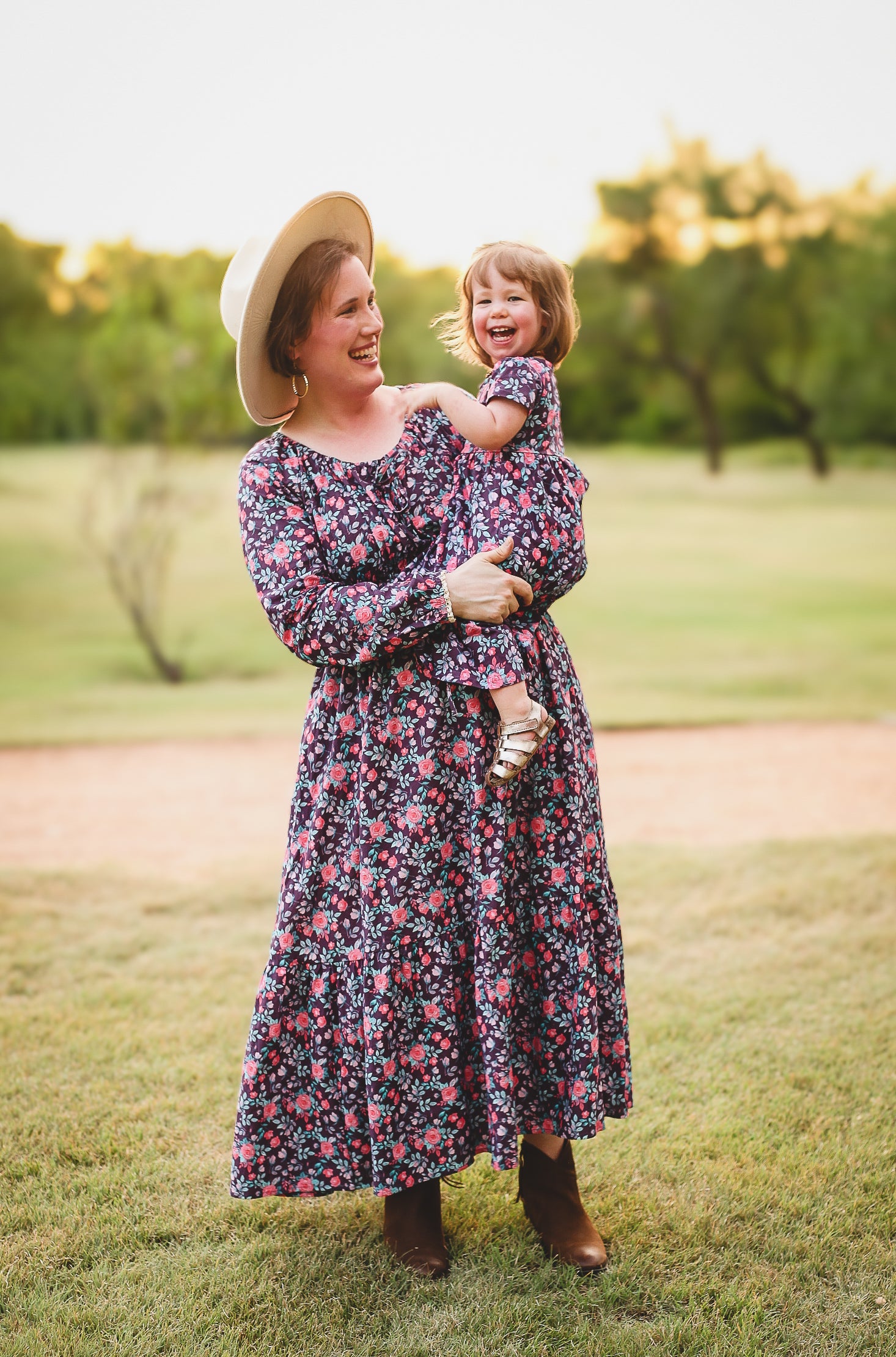 Woman in modest nursing floral dress holding child in park