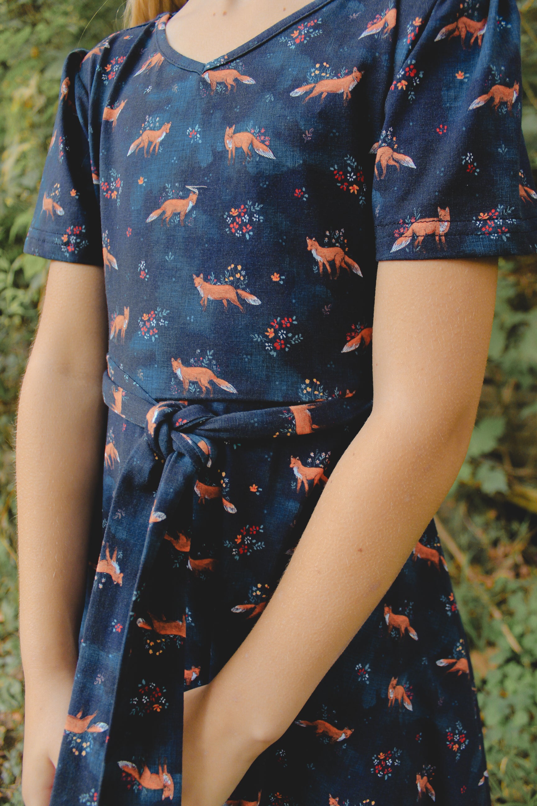 Person wearing modest navy fox-patterned dress against natural background