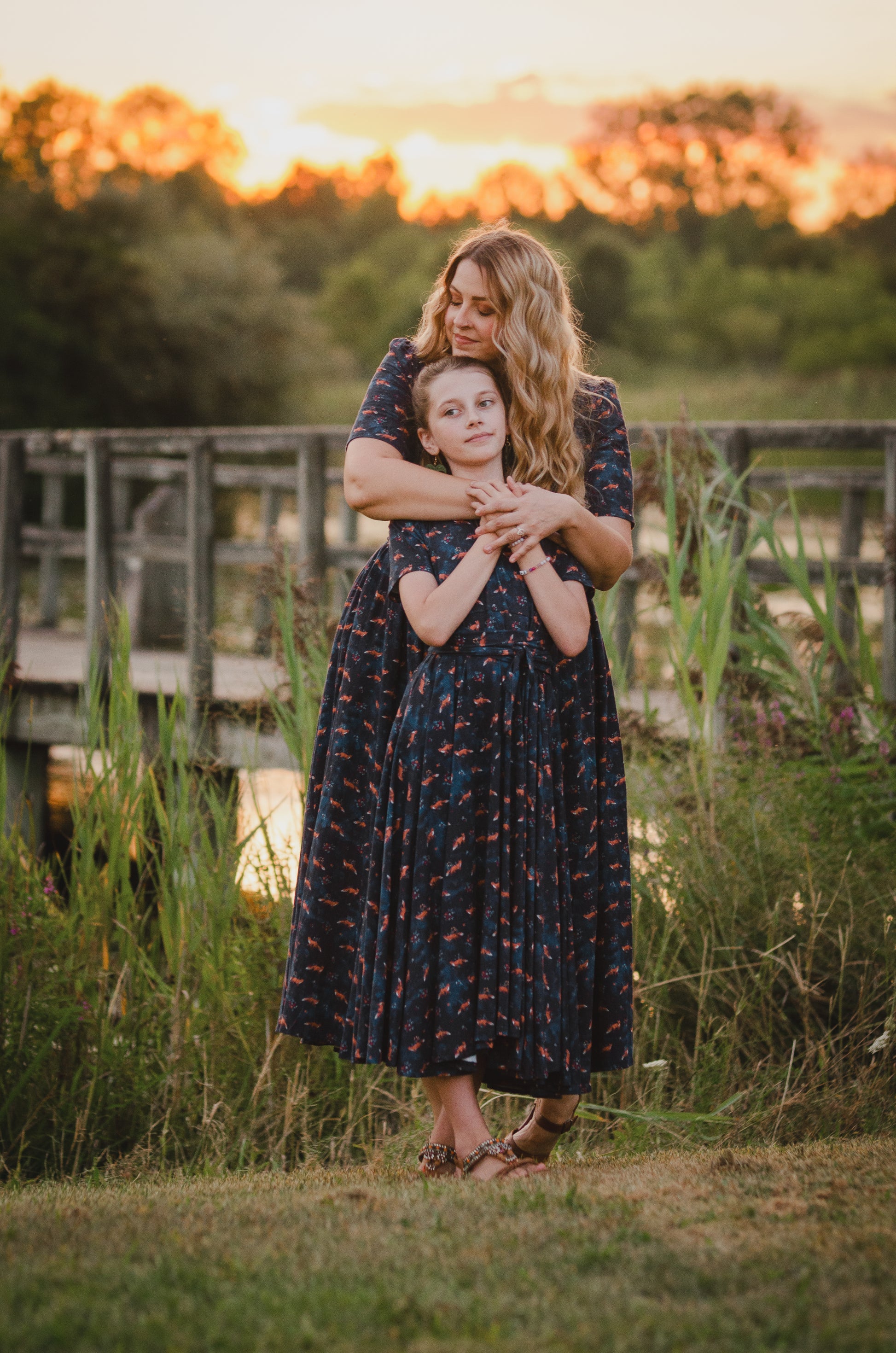 Woman in modest nursing dress with child, sunset field