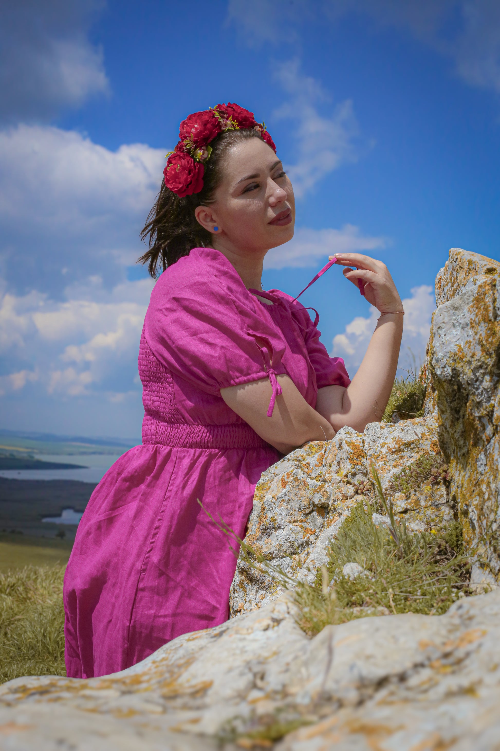 Woman in a pink modest nursing dress standing on rocks with a scenic background