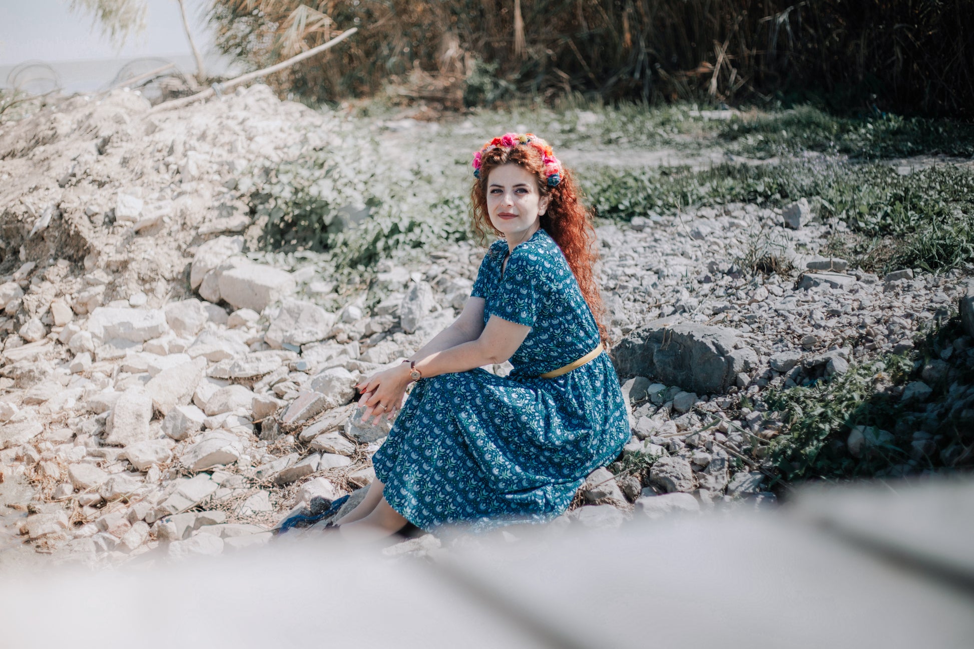 Woman in modest nursing dress on rocks outdoors.