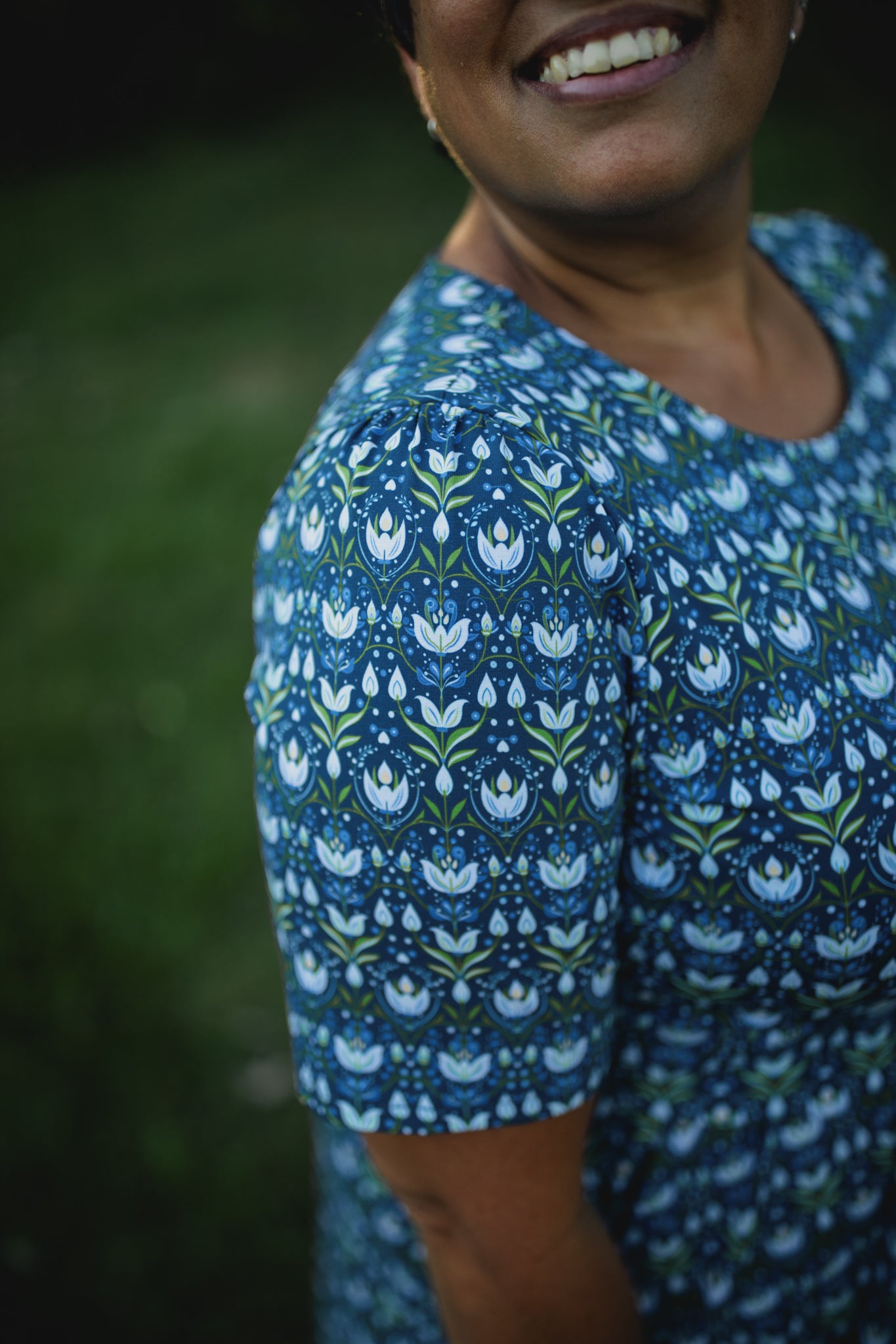 Woman in modest nursing dress, green background.