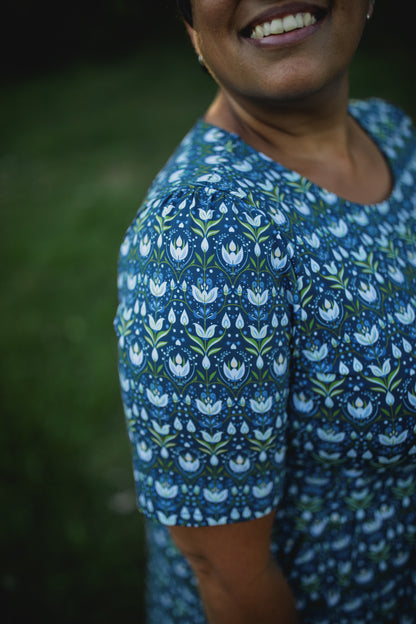 Woman in modest nursing dress, green background.
