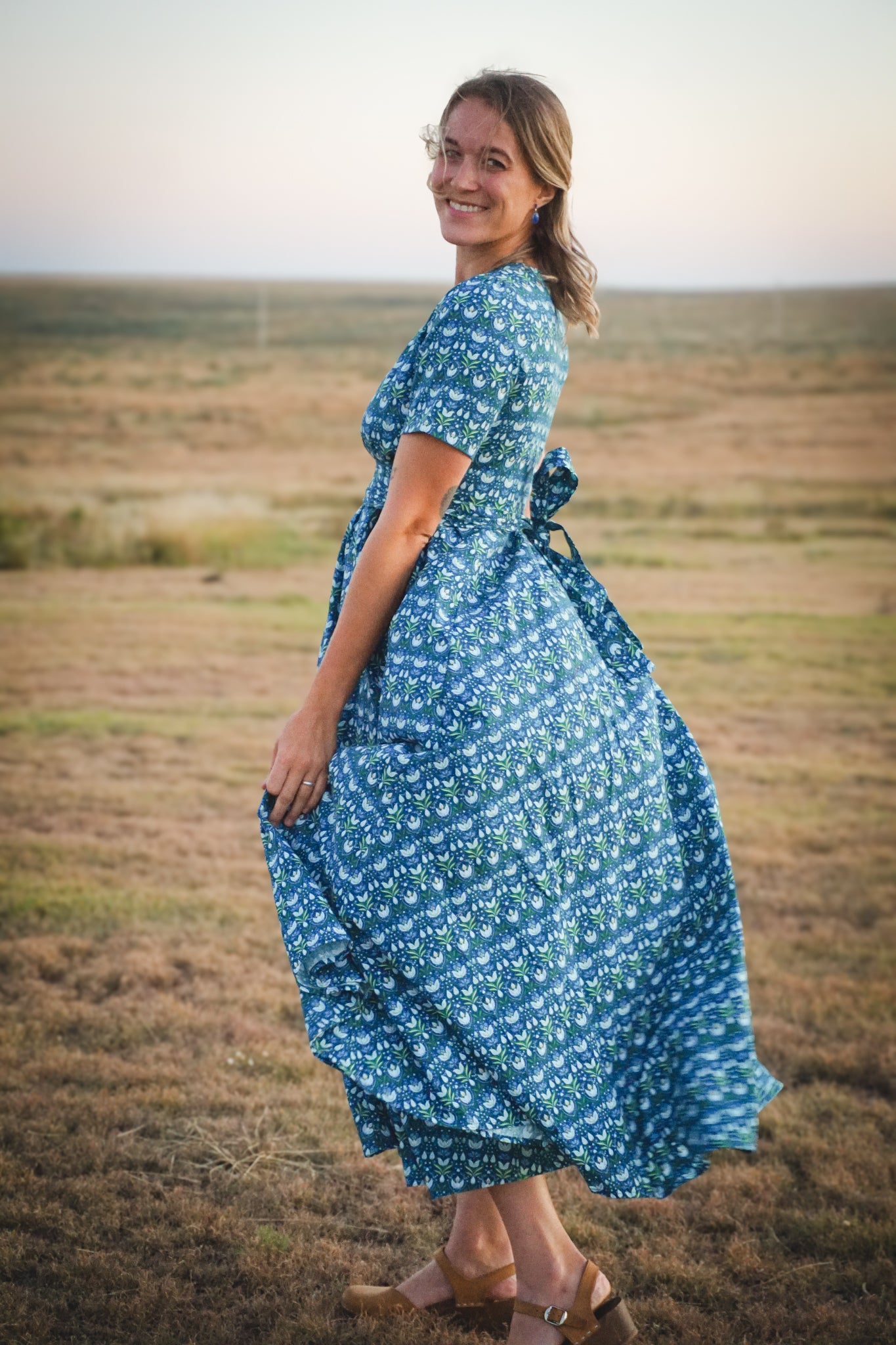 Woman in modest nursing dress in field at sunset