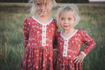 Two young girls in modest red floral dresses