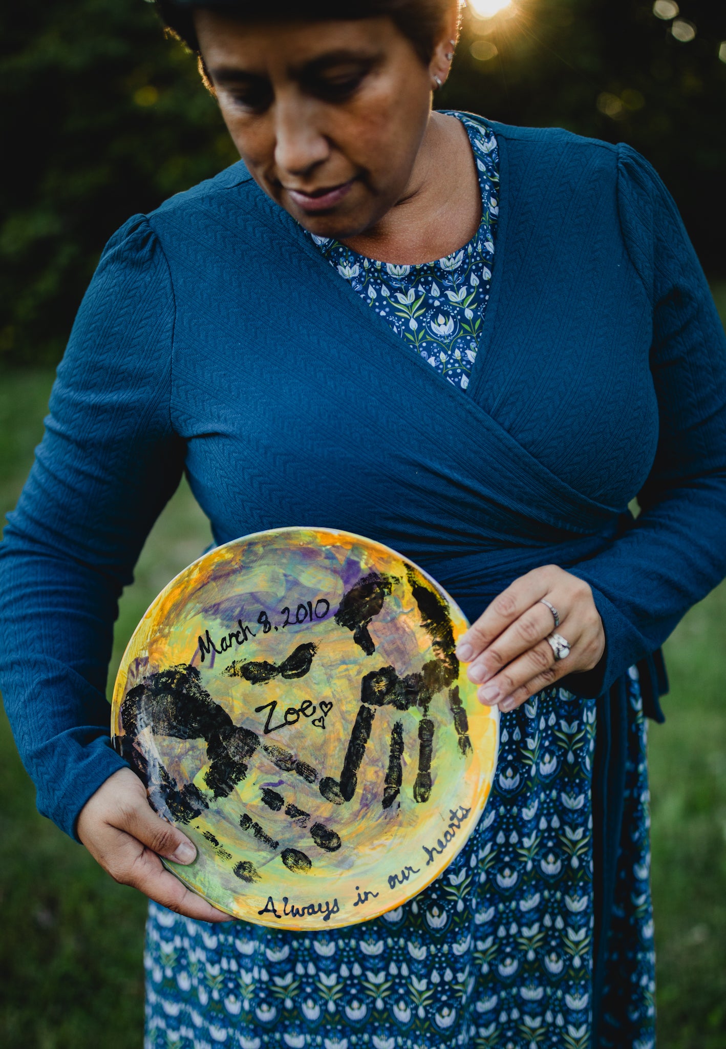 Woman holding painted plate with names outdoors.