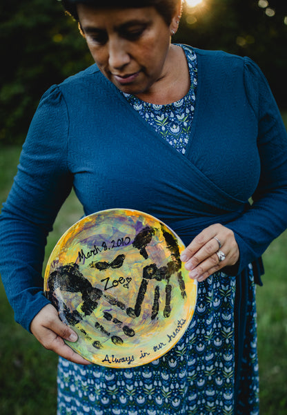 Woman holding painted plate with names outdoors.