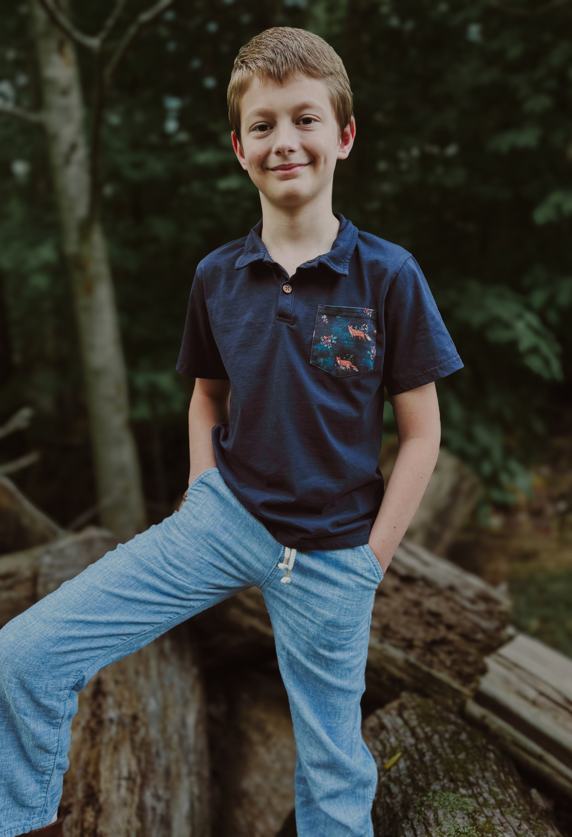 Boy wearing blue polo and jeans outdoors.