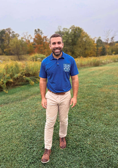 Man in blue polo in grassy field.