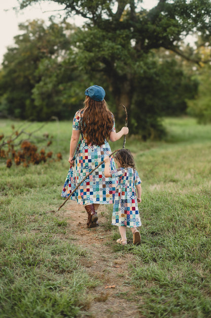 Mother and daughter in colorful modest dresses walking along a path in a natural setting.