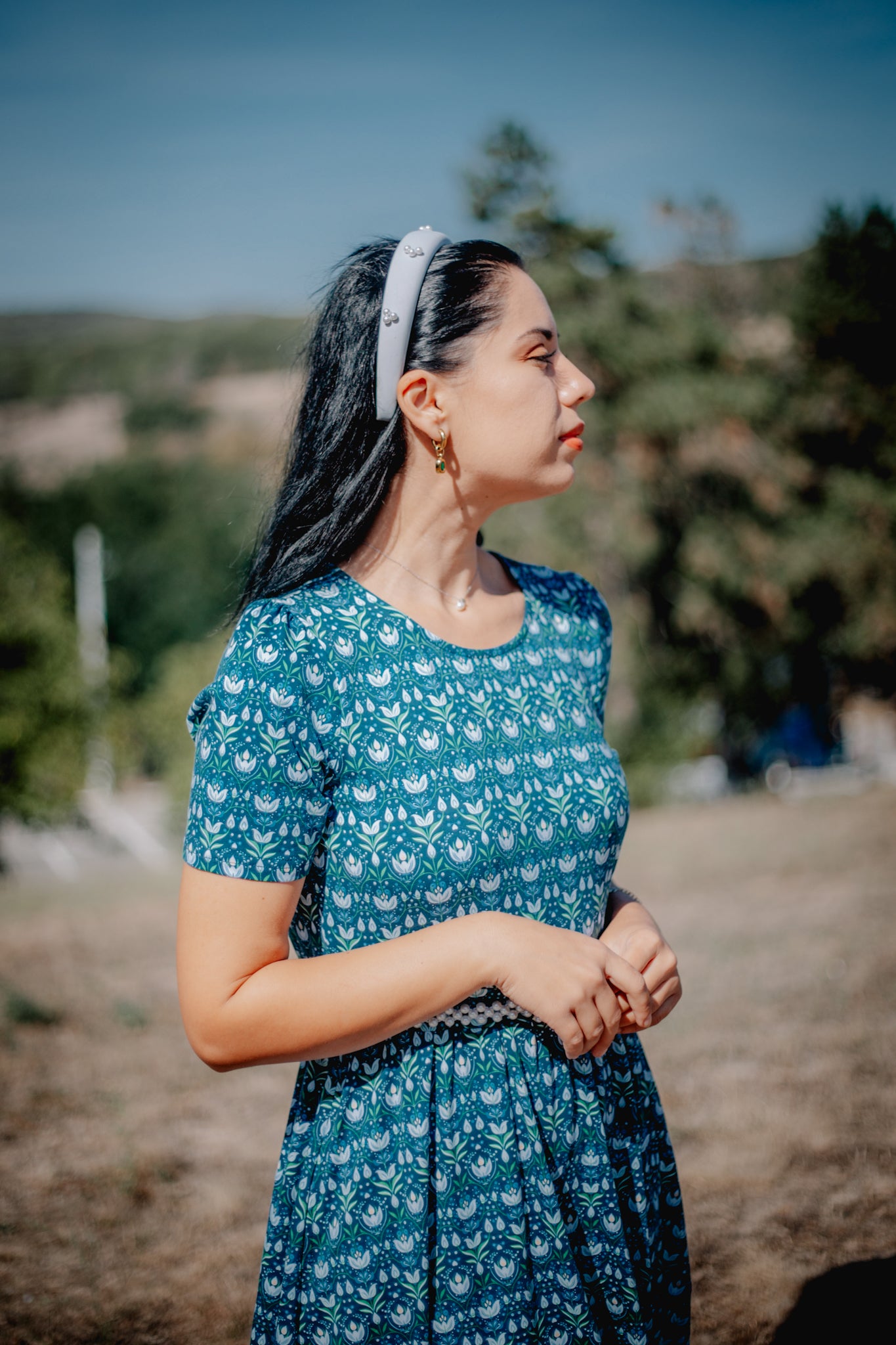 Woman in modest nursing dress outdoors with greenery