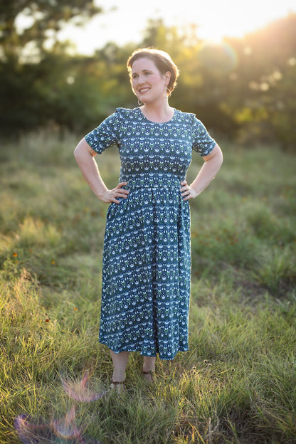 Woman in modest nursing dress, blue floral field.