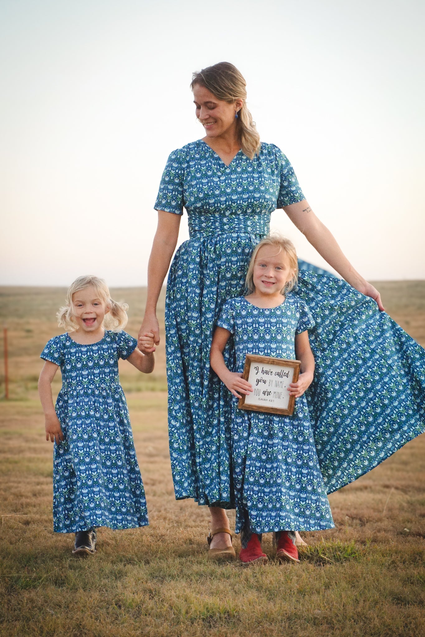 Mother in modest nursing dress with children in field