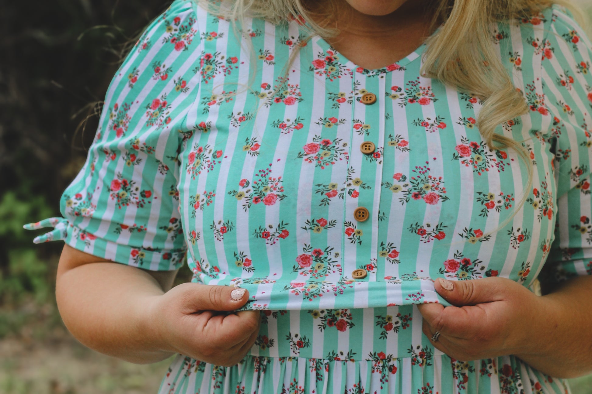 Person wearing a green and white striped modest nursing dress with floral patterns.
