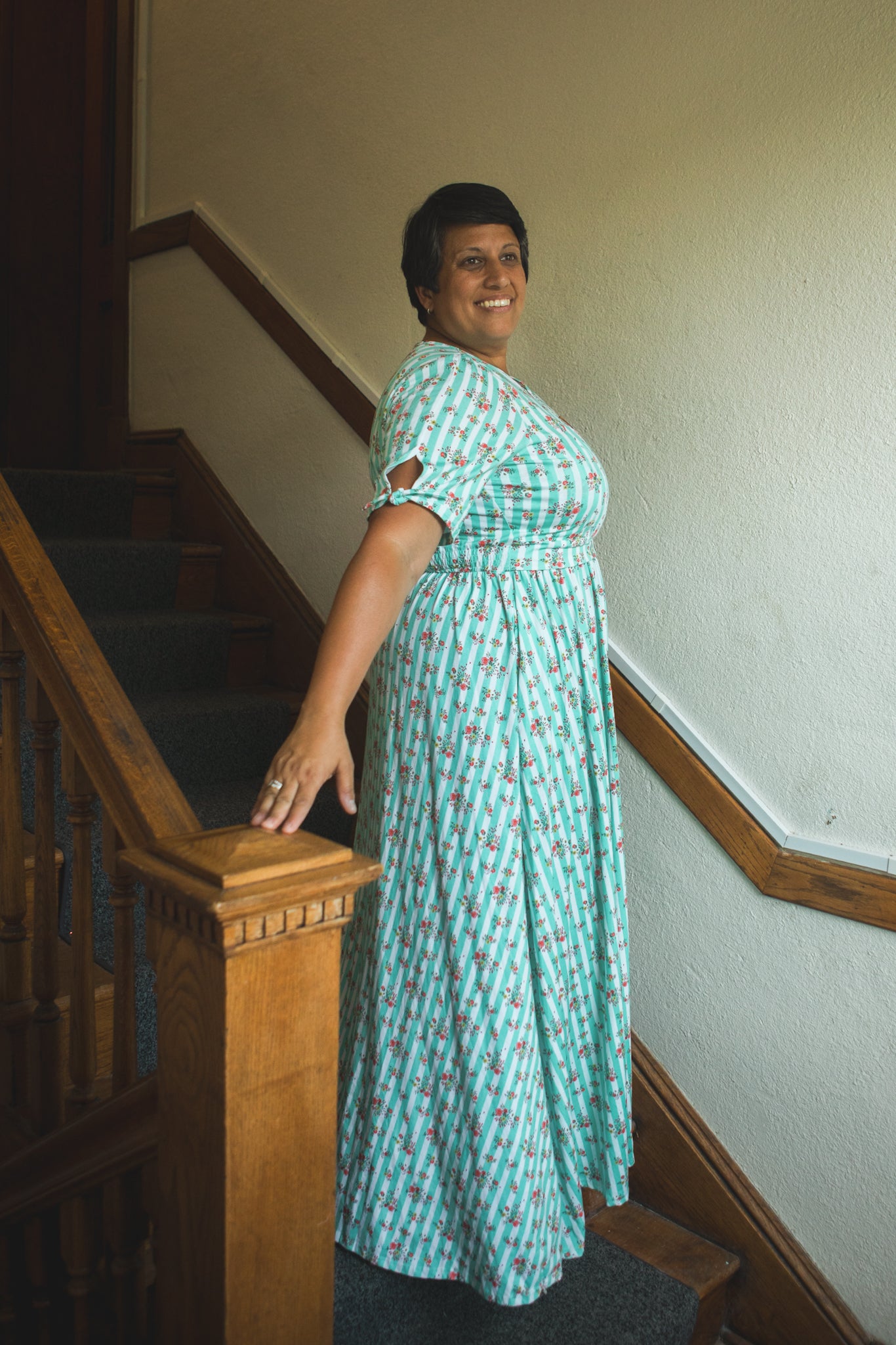 Woman in a green modest nursing dress standing on a staircase