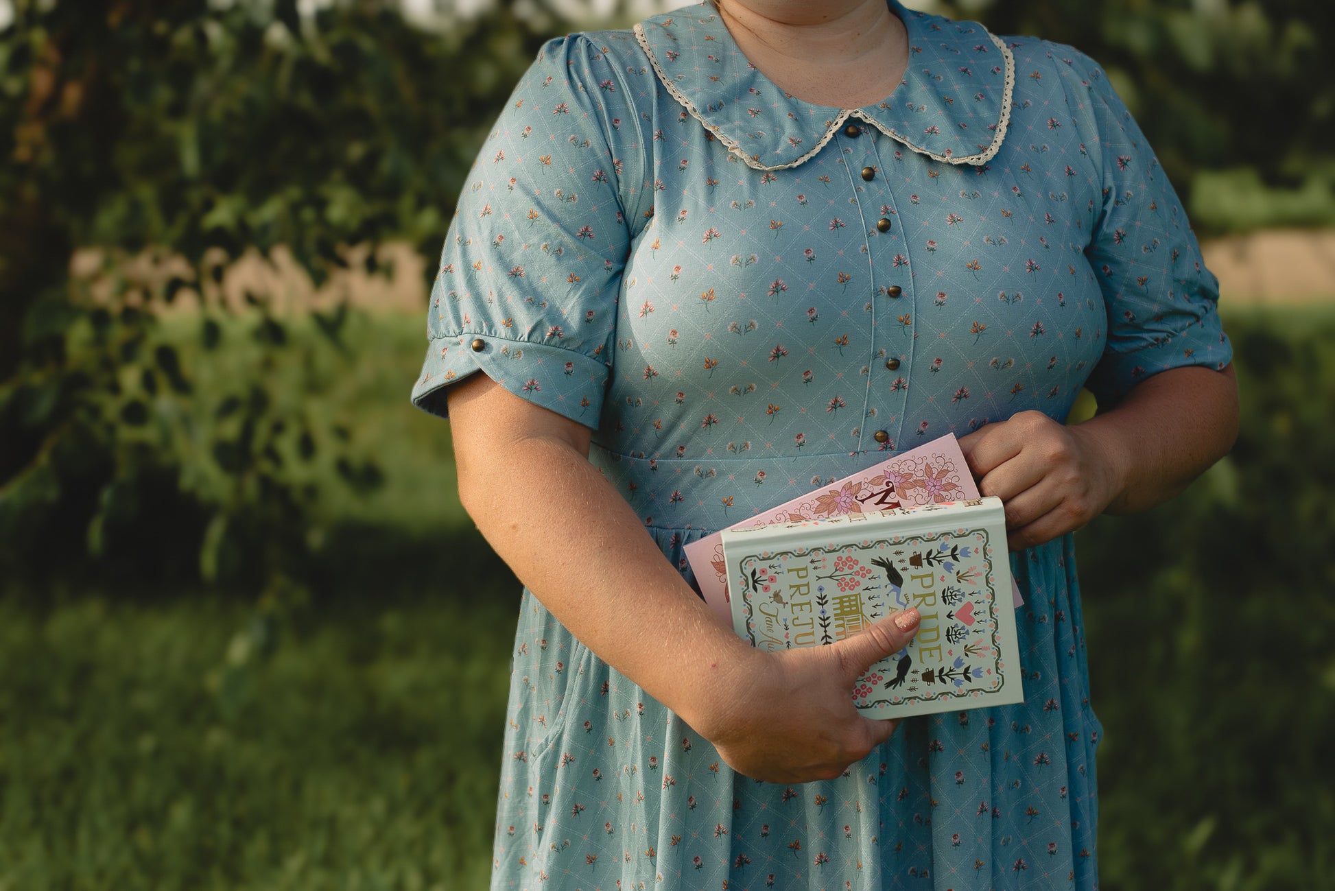 Person in a blue modest nursing dress holding books outdoors