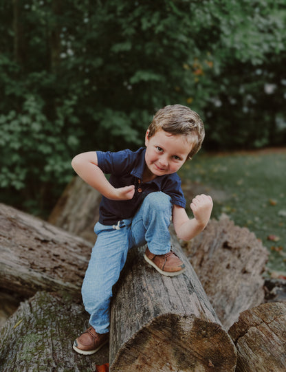 Child sitting on log in nature.