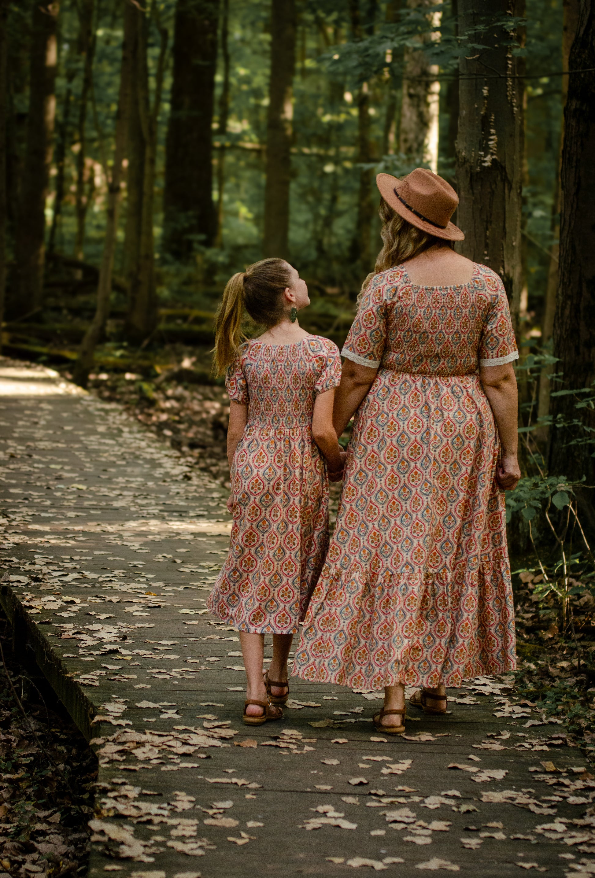 Woman wearing a patterned modest nursing dress with her daughter wearing a matching dress