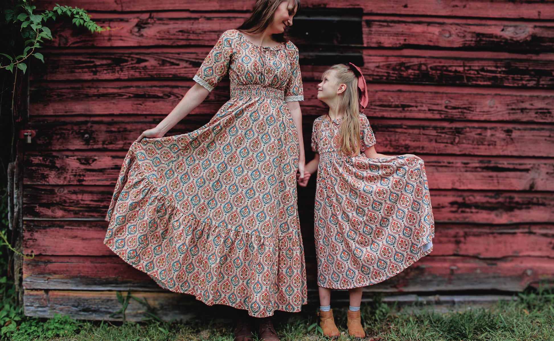 Woman wearing a patterned modest nursing dress with her daughter wearing a matching dress