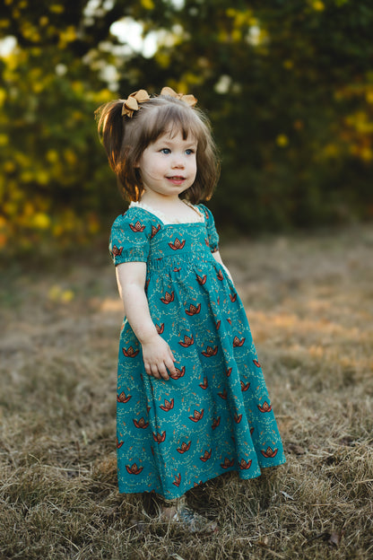 Young girl wearing modest dress in field outdoors.
