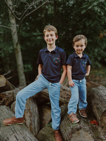 Two boys in navy polos on logs.
