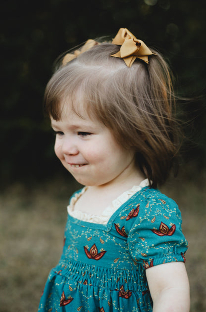 Young girl wearing modest dress with bow outdoors