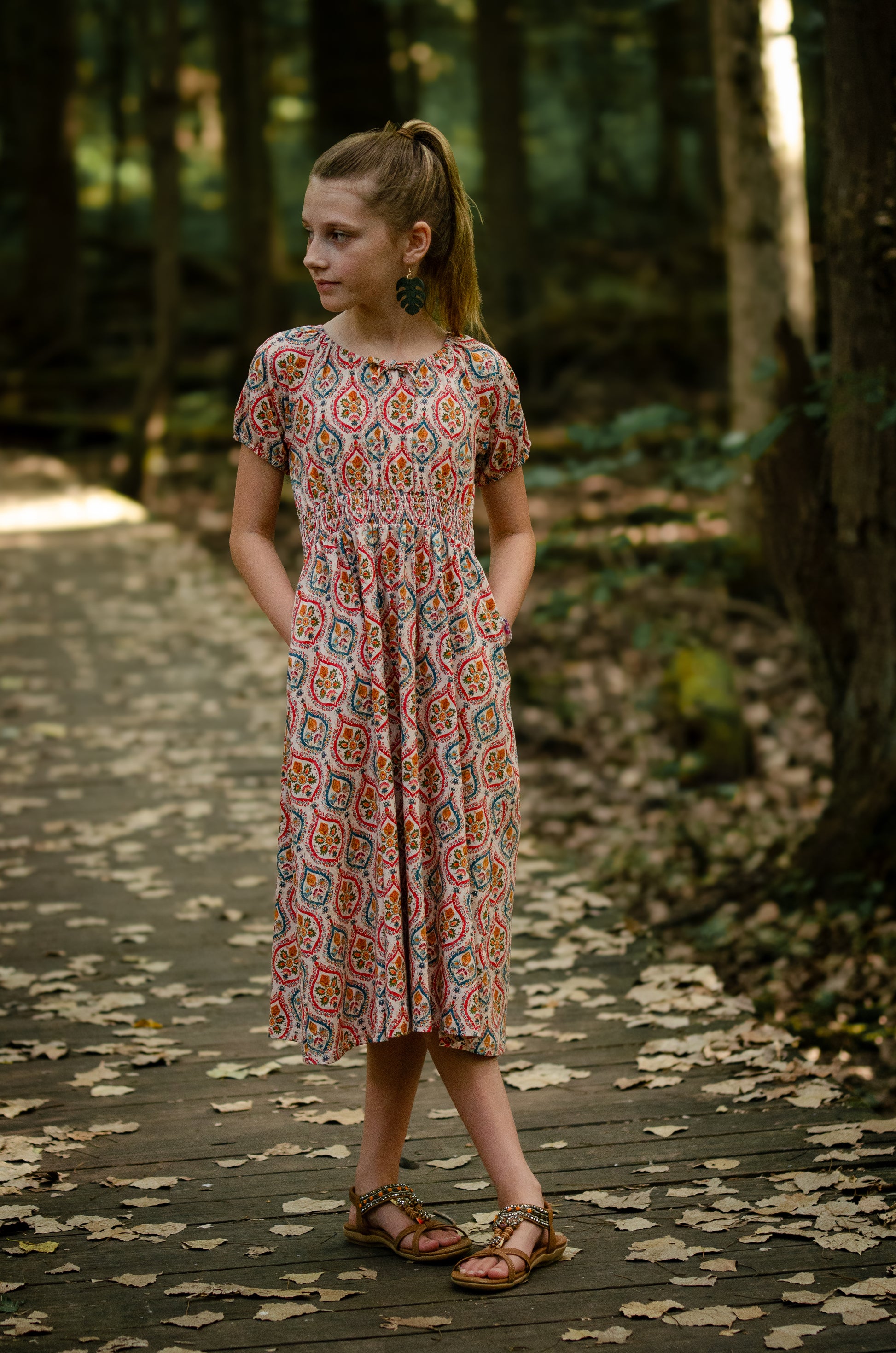 Young girl in patterned dress on forest path