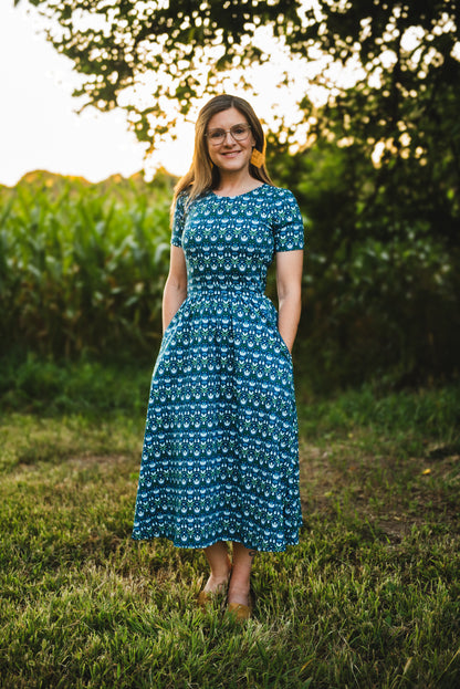 Woman in modest nursing dress, blue field trees.