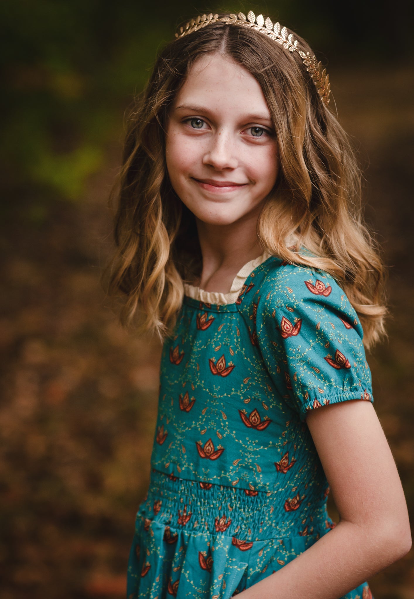 Young girl wearing modest dress with tiara outdoors.