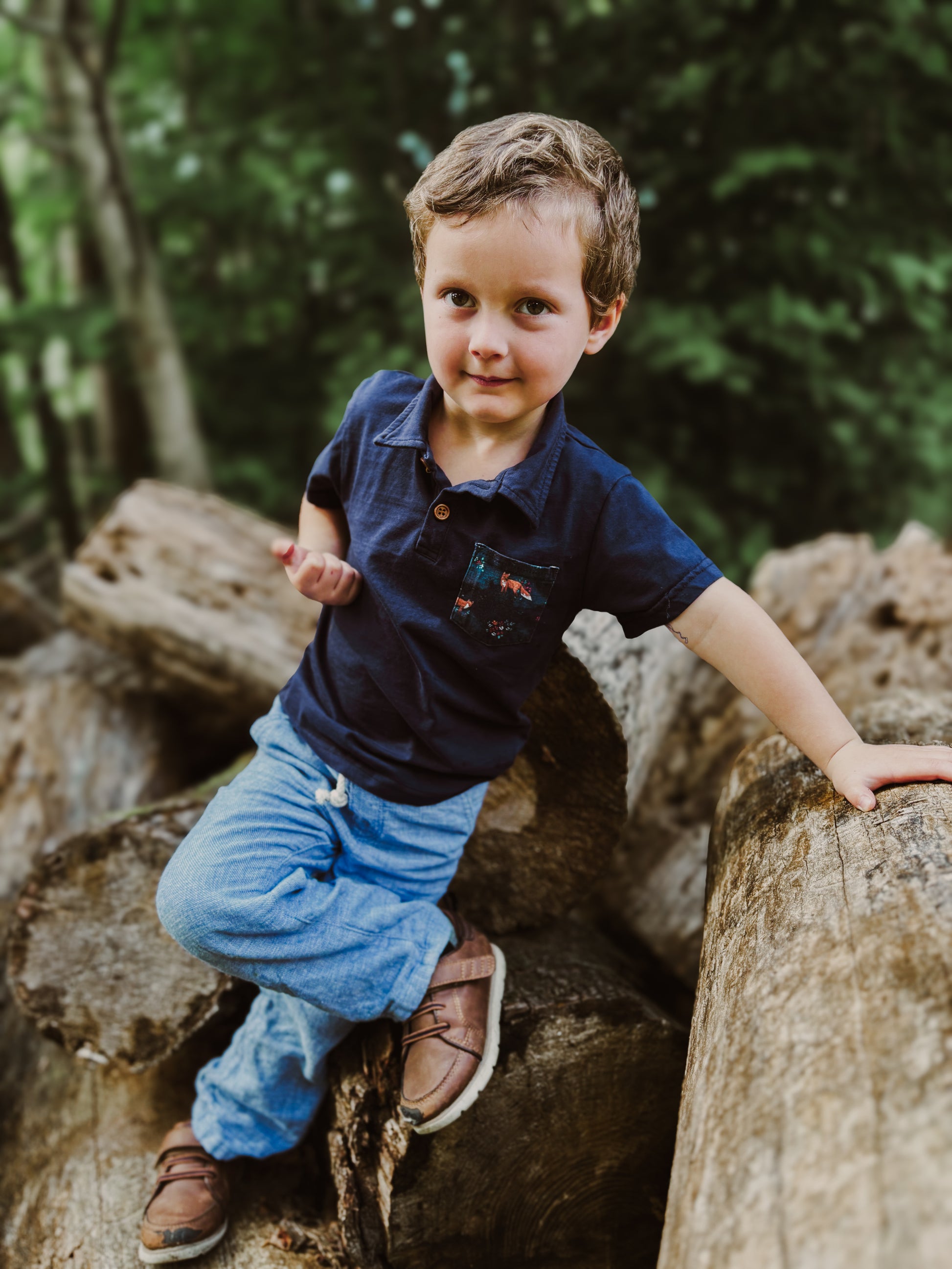 Boy in blue shirt on logs.