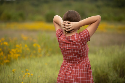 Woman in modest red dress, nursing-friendly design.