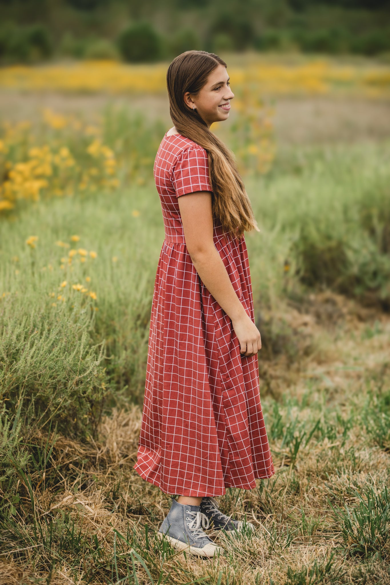 Woman in modest plaid dress, nursing-friendly design.