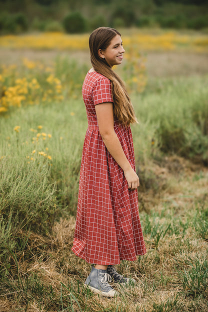 Woman in modest plaid dress, nursing-friendly design.