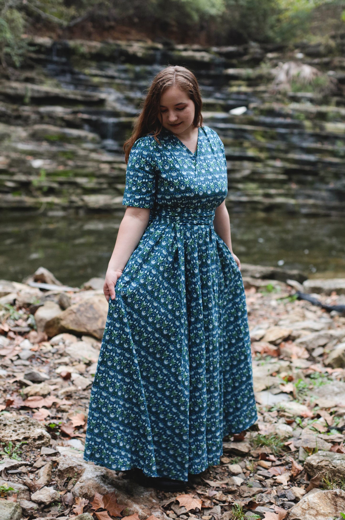 Woman in modest nursing dress by stream