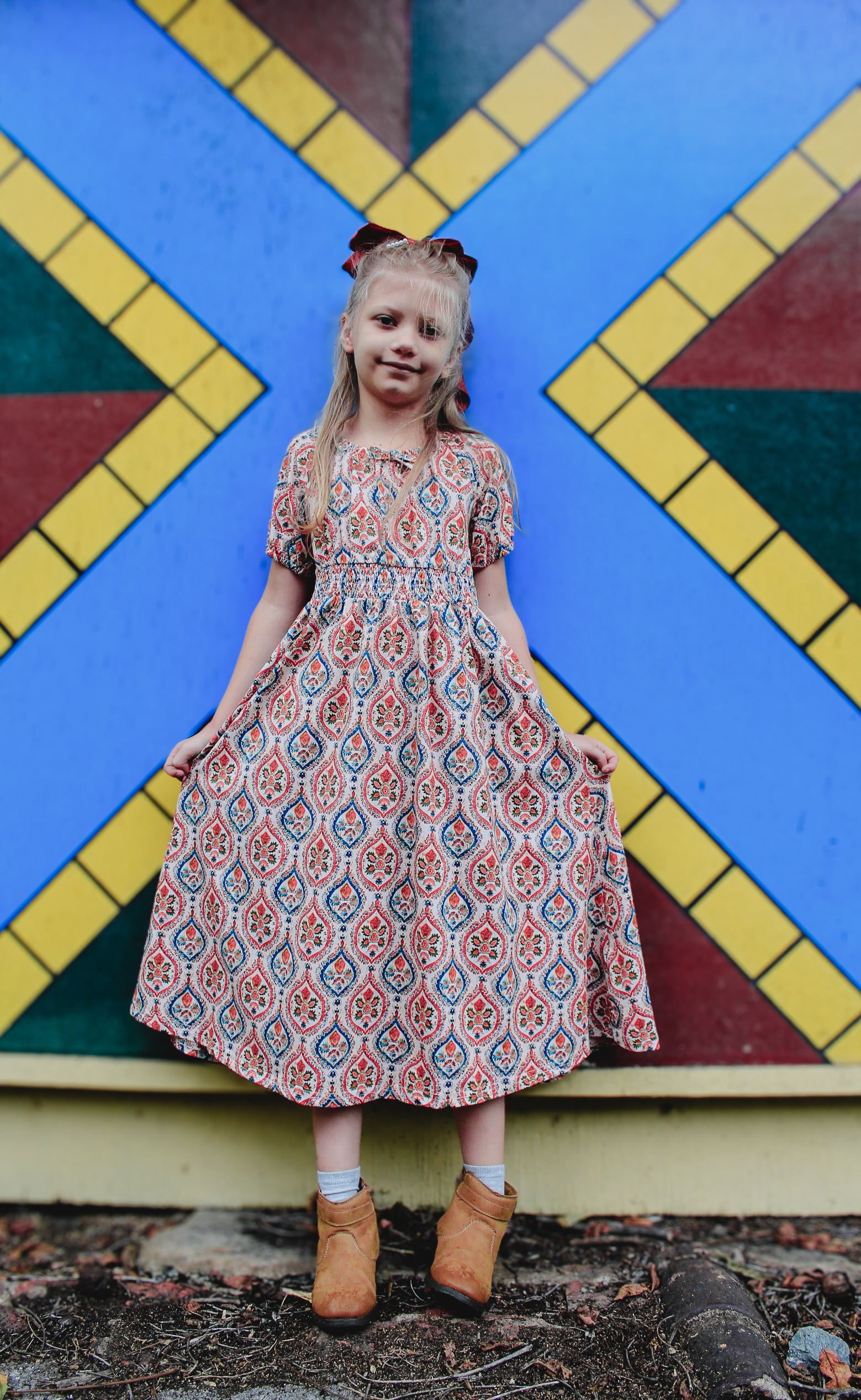 Young girl in patterned dress by geometric wall